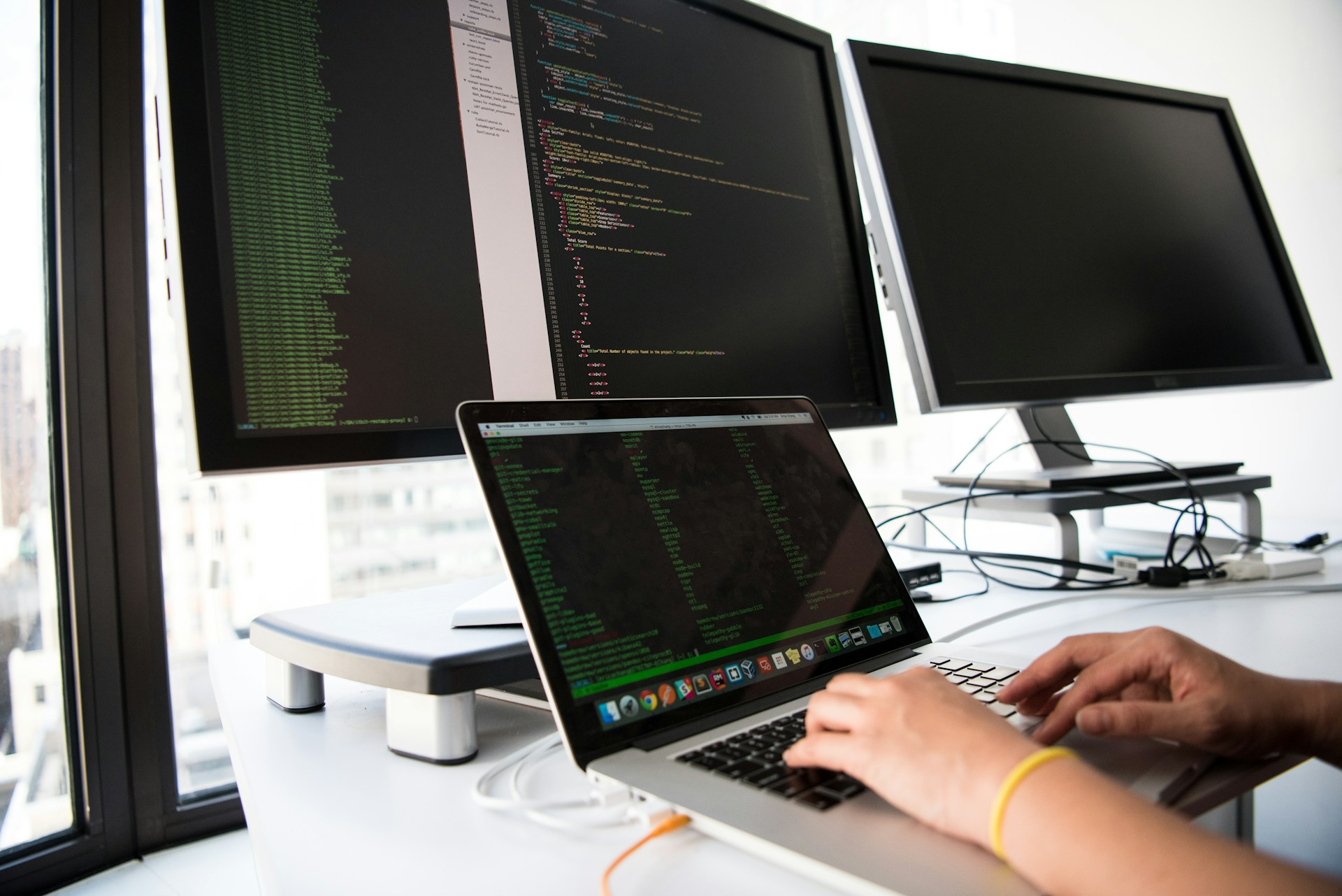 Postazione di sviluppo software con codice su più schermi